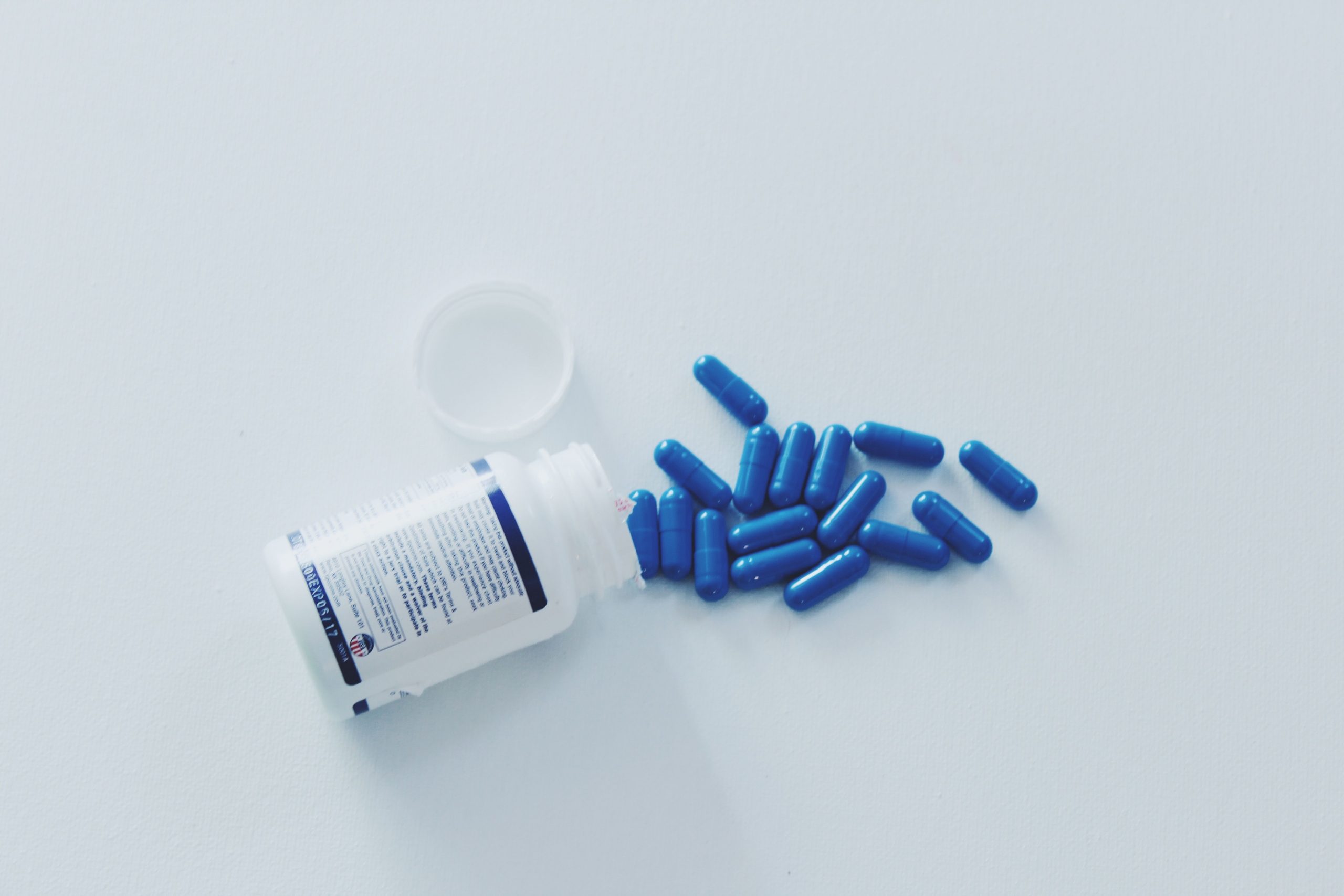 high angle view of capsules and pill bottle on white background