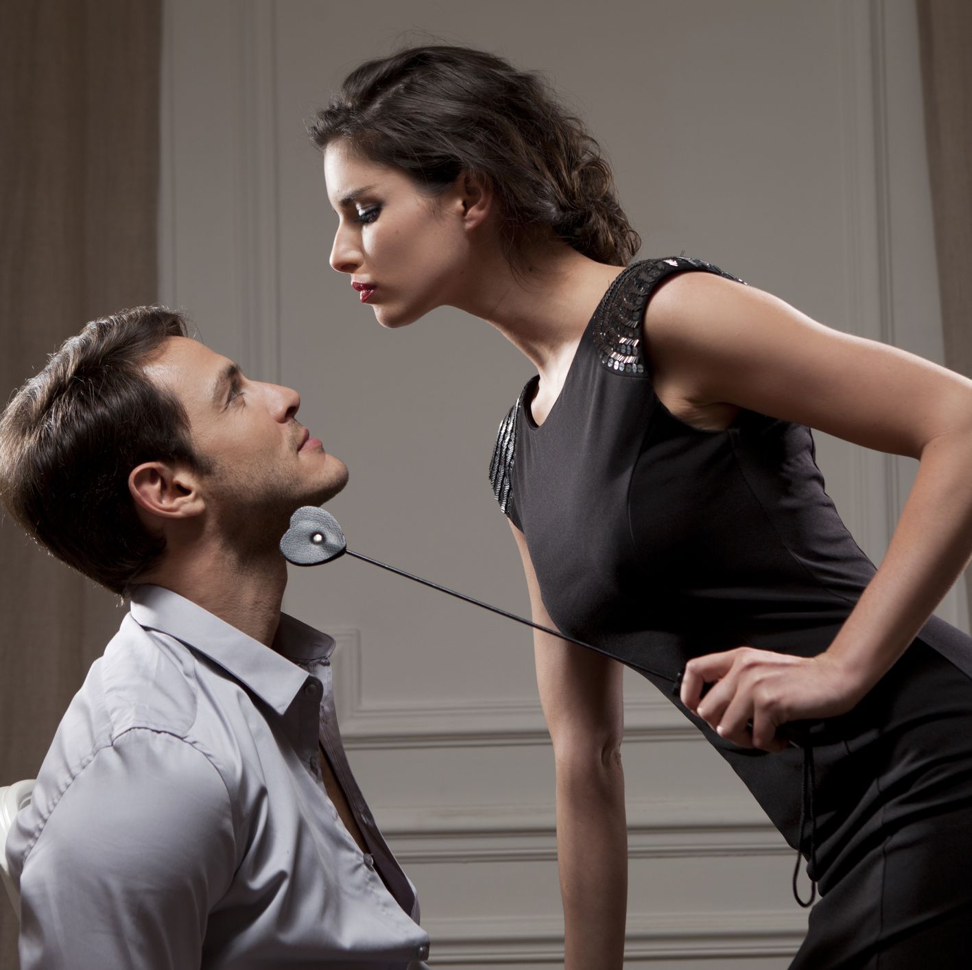 young woman dominating a man with a whip